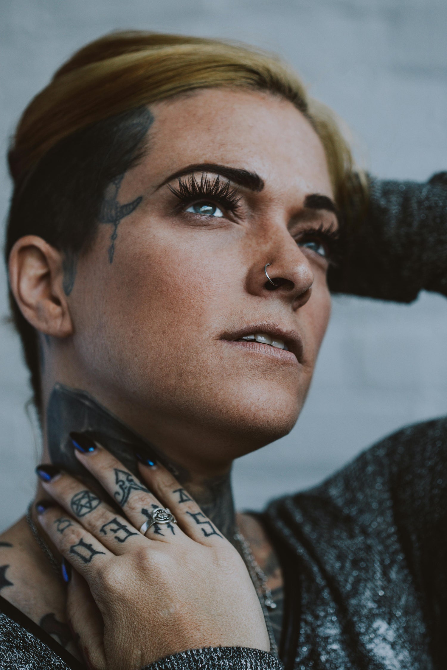 Person showcasing Hoops Piercing with nose ring and tattoos, highlighting stylish body art and elegance.